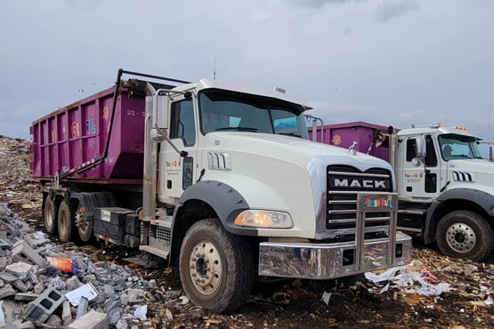 Cropped front angled view of Trash Gurl waste removal trucks.